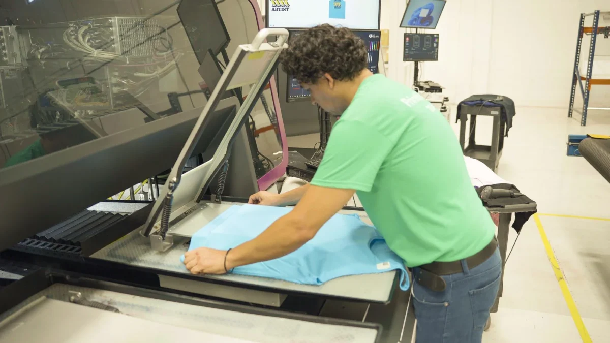 A print operator preparing fabric at a printing machine.