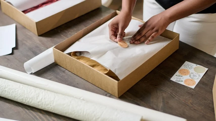 Hands carefully wrapping a garment in a presentation box