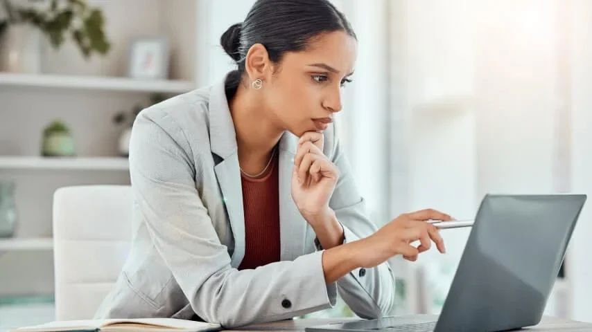 Reviewing a project and taking notes at a laptop.