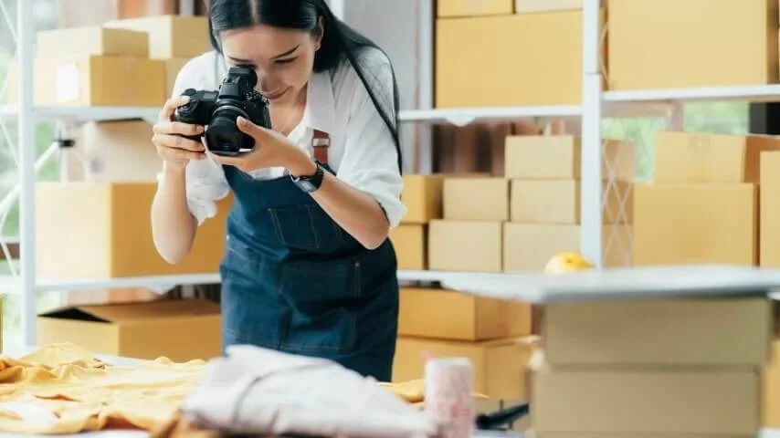 A photographer photographing products beside packaging boxes.