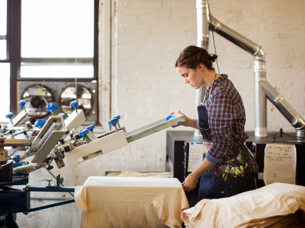 A production worker handling apparel at a print station.