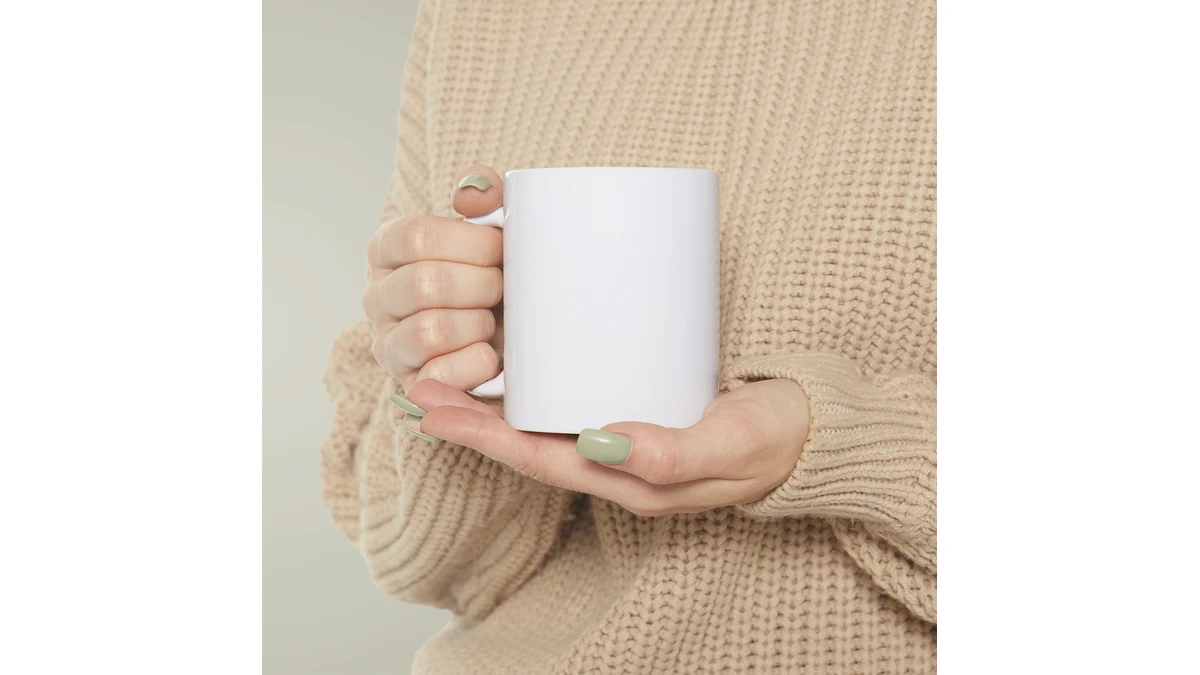 A person holding a plain white ceramic mug, shown as a model reference.